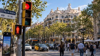 Semáforo en rojo para peatones y vehículos en el Paseo de Gracia con la Casa Milá al fondo.