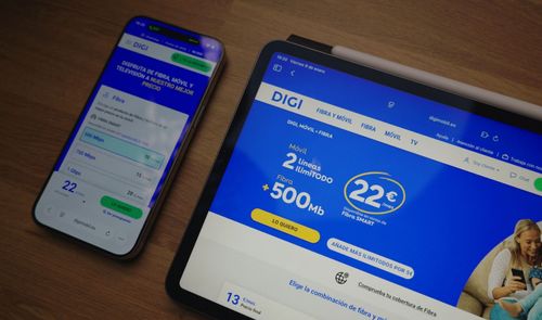 Página web de DIGI abierta en una tableta y un teléfono móvil sobre una mesa de madera.