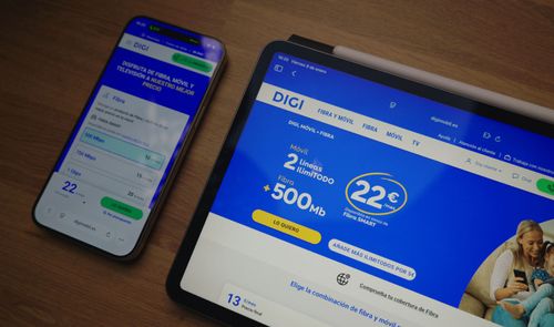 Sitio web de DIGI mostrado en las pantallas de un teléfono móvil y una tableta sobre una mesa de madera.