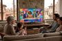 Familia viendo la televisión con interfaz DVB-I en un salón rústico.