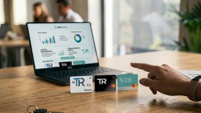 Tarjetas físicas de Revolut, Trade Republic y N26 frente a un ordenador portátil con interfaz de banca digital.