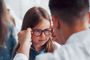 Niña probándose unas gafas graduadas con la ayuda de un óptico en una consulta profesional.