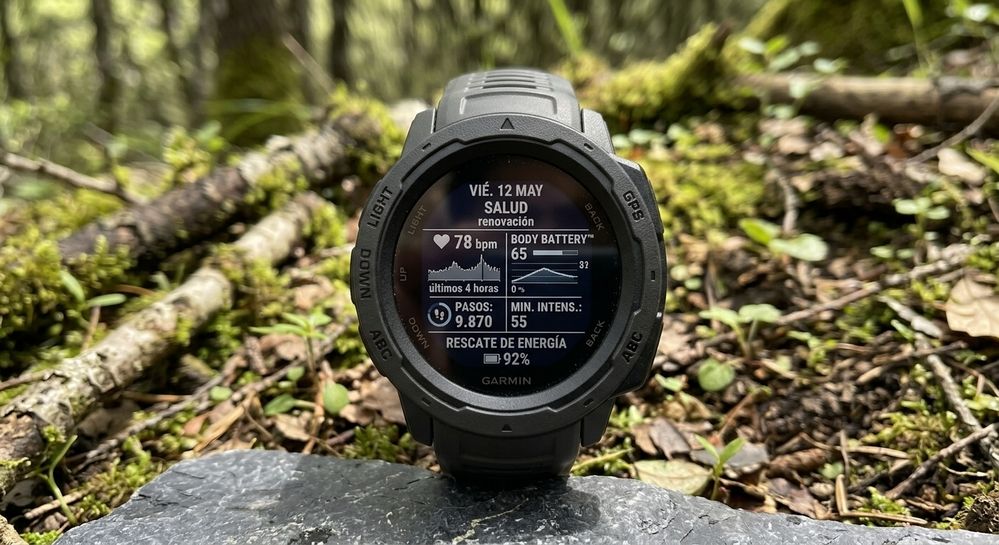 Reloj inteligente Garmin mostrando métricas de salud y Body Battery en un entorno natural.