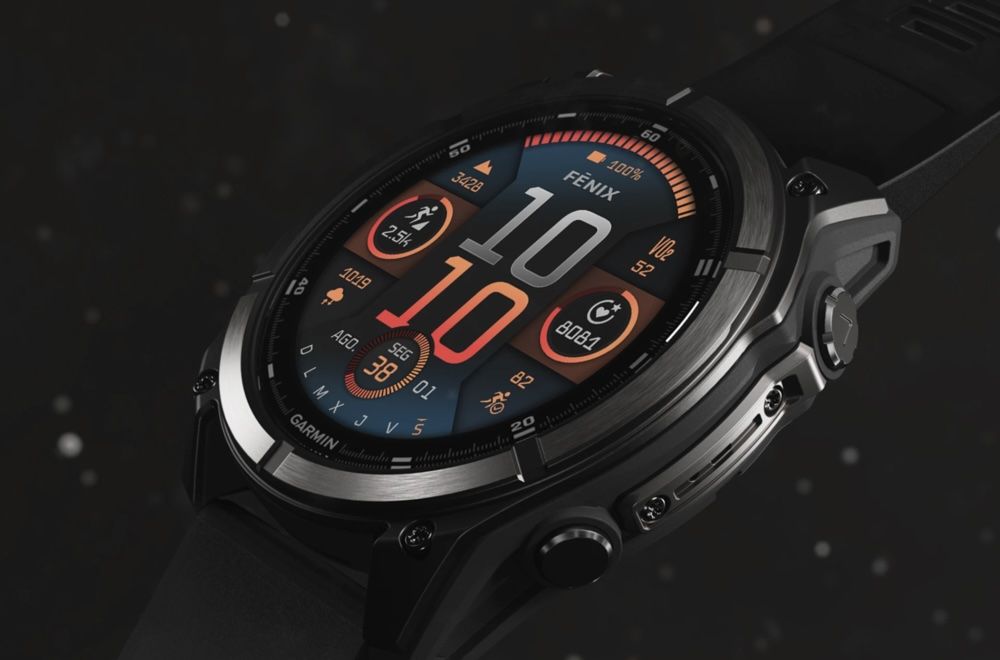 Primer plano lateral de un reloj inteligente Garmin Fenix con pantalla encendida mostrando métricas deportivas y hora digital.