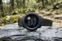 Reloj Garmin sobre una roca en el bosque mostrando un aviso de actualización completada en su pantalla.