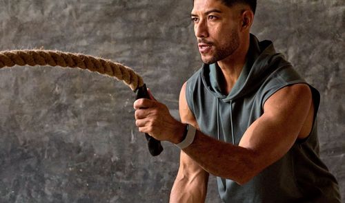 Hombre realizando ejercicio de cuerdas de batalla con un dispositivo Garmin Cirqa en la muñeca.