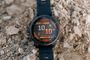 Reloj inteligente Garmin Fenix 8 apoyado sobre rocas en un entorno exterior.
