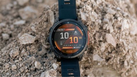 Reloj inteligente Garmin Fenix 8 apoyado sobre rocas en un entorno exterior.