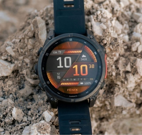 Reloj inteligente Garmin Fenix 8 apoyado sobre rocas en un entorno exterior.