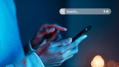 Persona utilizando un smartphone en un entorno con iluminación azulada junto a una barra de búsqueda digital.