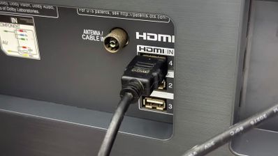Primer plano de un cable HDMI conectado al puerto número 4 del panel trasero de una Smart TV, junto a entradas de antena y USB.