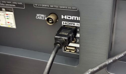 Primer plano de un cable HDMI conectado al puerto número 4 del panel trasero de una Smart TV, junto a entradas de antena y USB.