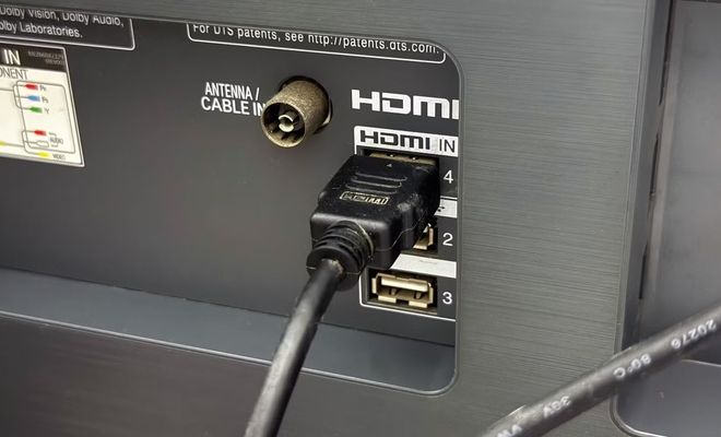Primer plano de un cable HDMI conectado al puerto número 4 del panel trasero de una Smart TV, junto a entradas de antena y USB.