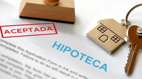 Contrato de hipoteca con el sello rojo de aceptada junto a unas llaves de casa.