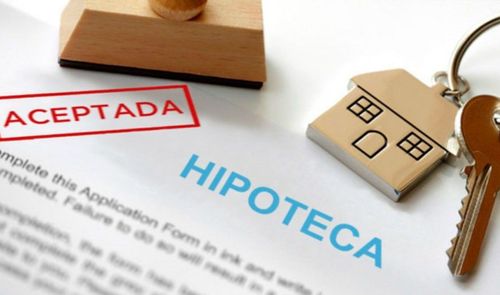 Contrato de hipoteca con el sello rojo de aceptada junto a unas llaves de casa.
