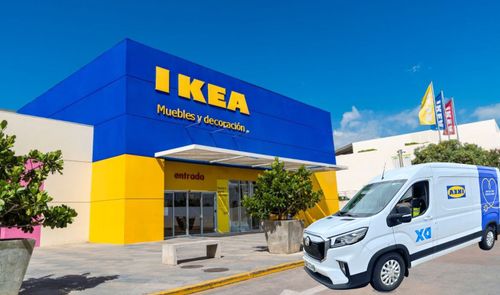 Fachada de una tienda IKEA de color azul y amarillo con una furgoneta de reparto blanca en primer plano.