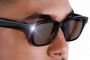 Detalle de una persona usando gafas inteligentes con una luz LED blanca encendida en el frontal de la montura.