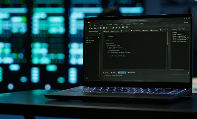 Ordenador portátil con editor de código abierto en pantalla ante un fondo desenfocado de centros de datos.