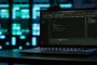 Ordenador portátil con editor de código abierto en pantalla ante un fondo desenfocado de centros de datos.