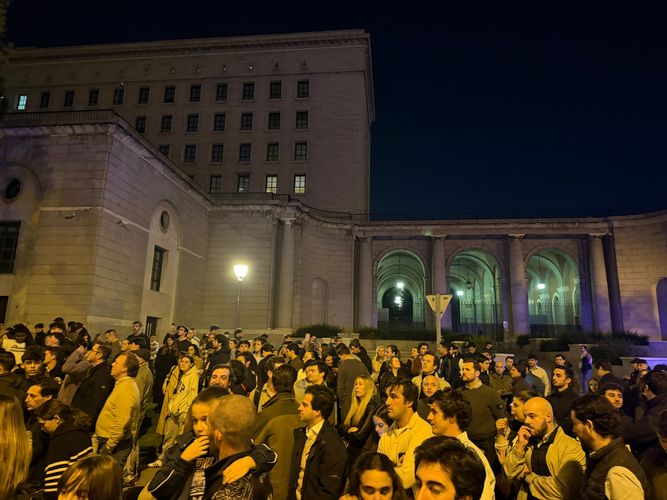 Multitud de personas concentradas de noche frente a la fachada iluminada del Ministerio de Transportes.