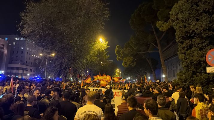 Multitud de personas concentradas de noche en una avenida con banderas y una pancarta frente al Ministerio de Transporte.