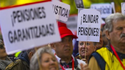 Personas mayores sostienen pancartas durante una manifestación por las pensiones en la calle.
