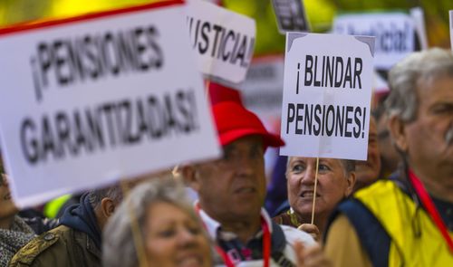 Personas mayores sostienen pancartas durante una manifestación por las pensiones en la calle.