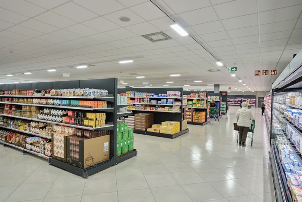 Pasillo central de un supermercado Mercadona con estanterías de alimentación y clientes comprando.