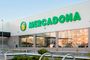 Fachada exterior de un supermercado Mercadona con el logotipo verde sobre fondo blanco y grandes cristaleras.