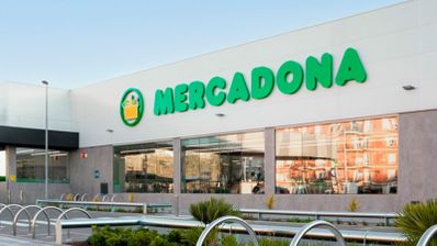 Fachada exterior de un supermercado Mercadona con el logotipo verde sobre fondo blanco y grandes cristaleras.
