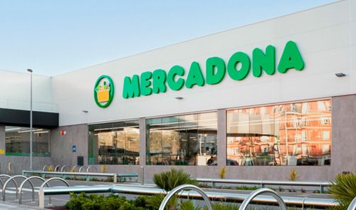 Fachada exterior de un supermercado Mercadona con el logotipo verde sobre fondo blanco y grandes cristaleras.