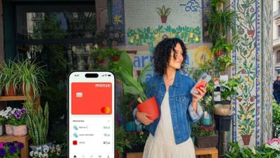 Interfaz de la aplicación Monzo Bank en un teléfono móvil junto a una mujer en una floristería.