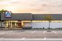 Fachada exterior de un supermercado Aldi con aparcamiento en primer plano al atardecer.