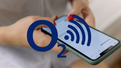 Primer plano de manos sosteniendo un smartphone con el logotipo de O2 y un símbolo de señal Wi-Fi superpuestos.
