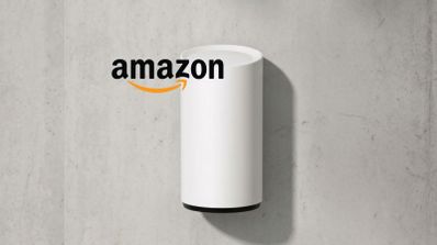 Altavoz inteligente cilíndrico de color blanco junto al logotipo de Amazon sobre una pared de hormigón.