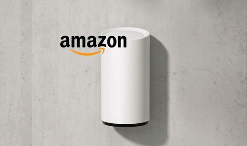 Altavoz inteligente cilíndrico de color blanco junto al logotipo de Amazon sobre una pared de hormigón.