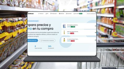 Interfaz de la web Preciosdelsuper en un ordenador portátil frente a un pasillo de supermercado.