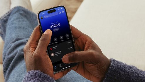 Primer plano de un usuario manejando la aplicación financiera Revolut en un smartphone para consultar el saldo y los últimos movimientos de la cuenta.