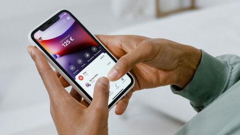 Persona manejando la aplicación de Revolut en un smartphone para consultar el saldo y las transacciones.