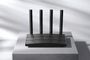 Router TP-Link de color negro con cuatro antenas verticales externas sobre un pedestal gris.
