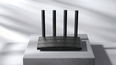 Router TP-Link de color negro con cuatro antenas verticales externas sobre un pedestal gris.