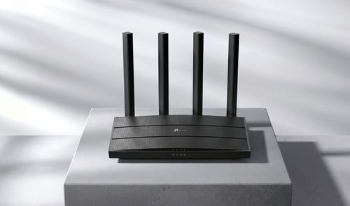 Router TP-Link de color negro con cuatro antenas verticales externas sobre un pedestal gris.