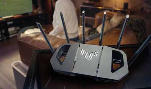 Router inalámbrico con seis antenas externas y logotipo frontal en un salón doméstico.