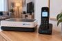 Router y teléfono inalámbrico de Movistar sobre un mueble de madera en un salón.