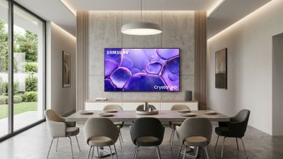 Televisor Samsung Crystal UHD instalado en la pared de un salón comedor moderno con iluminación cálida.