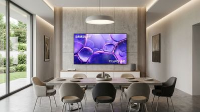 Televisor Samsung Crystal UHD instalado en la pared de un salón comedor moderno con iluminación cálida.