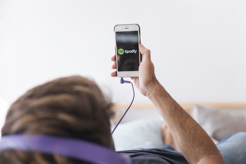 Persona utilizando la aplicación de Spotify en un smartphone mientras usa auriculares de diadema.