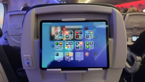 Tableta sujeta en el respaldo de un asiento de avión de easyJet mostrando iconos de aplicaciones.