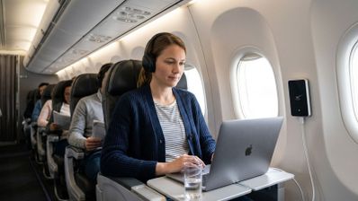 Pasajera utilizando un ordenador portátil en el asiento de un avión durante un vuelo.