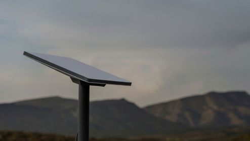 Antena parabólica rectangular de Starlink instalada en el exterior con montañas de fondo bajo un cielo nublado.